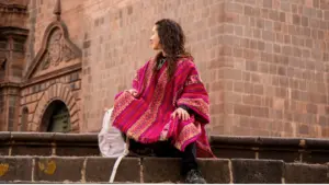 Photo of a woman wearing a poncho admiring the cathedral in Cusco's main square.