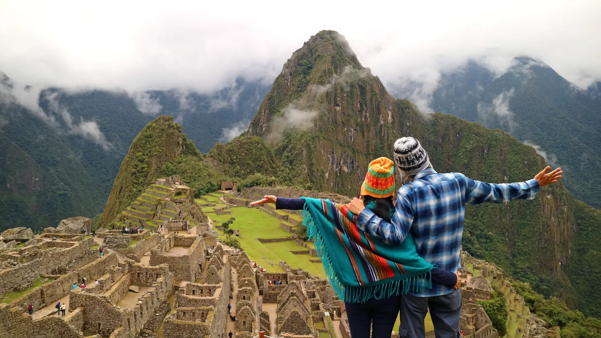 Couple enjoying the iconic view of Machu Picchu during a Machu Picchu day trip from Cusco, surrounded by lush mountains and ancient Inca ruins.